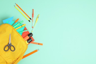 Photo of Backpack and different school supplies on turquoise background, flat lay. Space for text