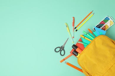 Backpack and different school supplies on turquoise background, flat lay. Space for text