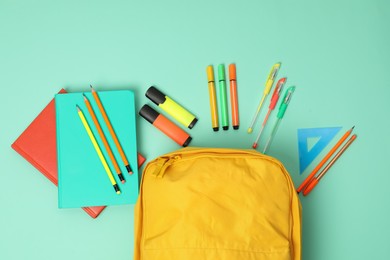 Backpack and different school supplies on turquoise background, flat lay