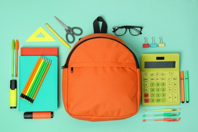 Backpack and different school supplies on turquoise background, flat lay