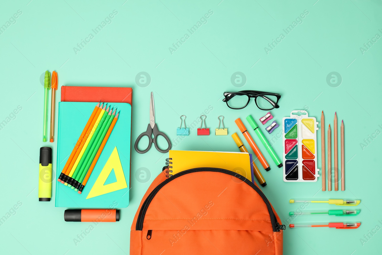 Photo of Backpack and different school supplies on turquoise background, flat lay