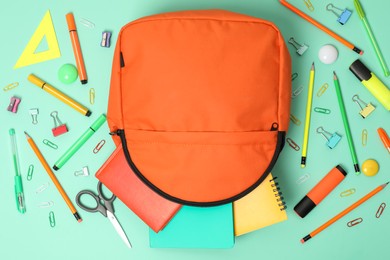 Photo of Backpack and different school supplies on turquoise background, flat lay