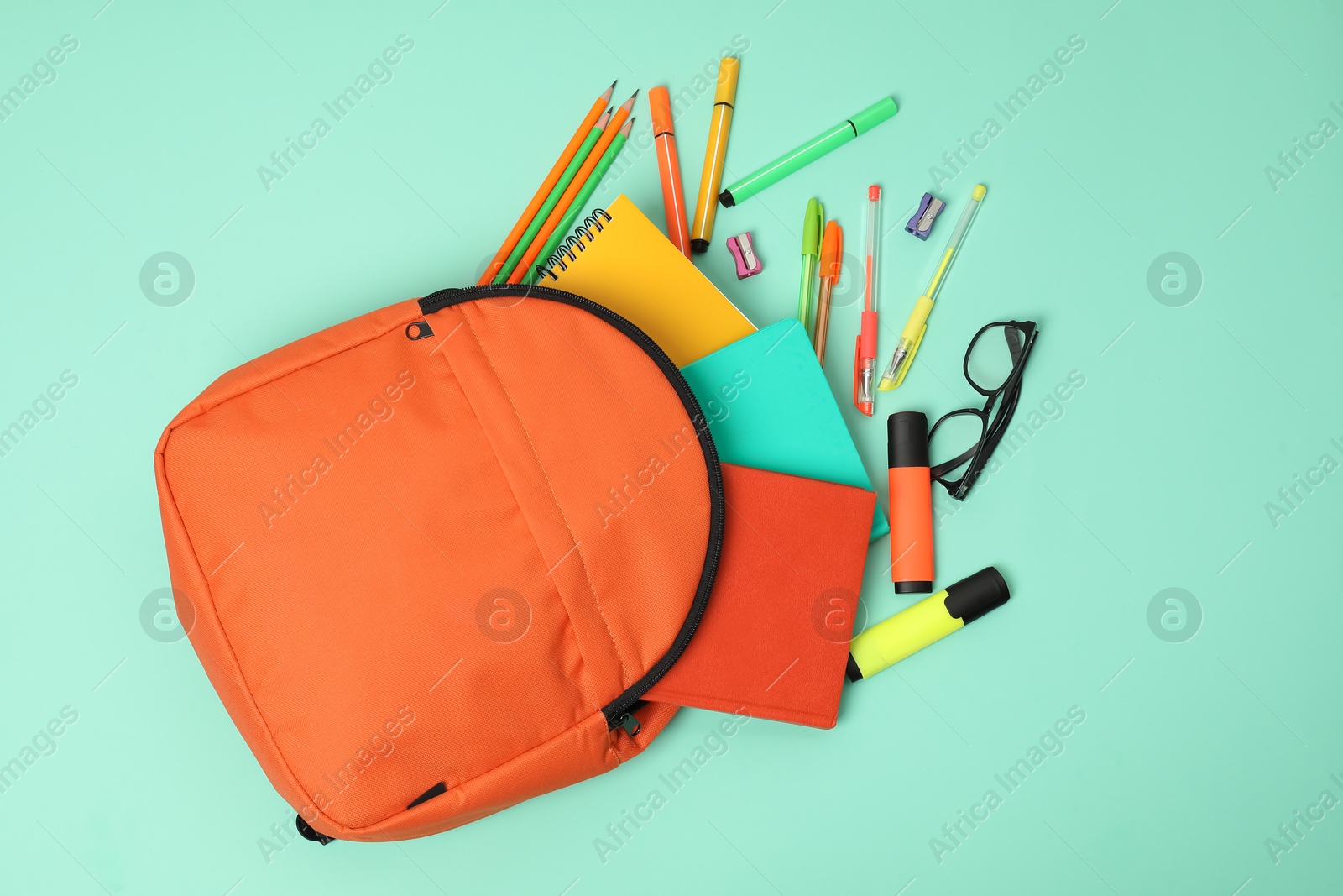 Photo of Backpack and different school supplies on turquoise background, flat lay