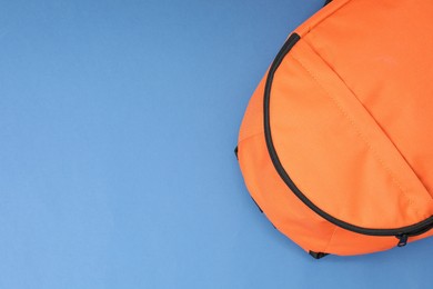 Photo of Orange backpack on blue background, top view. Space for text