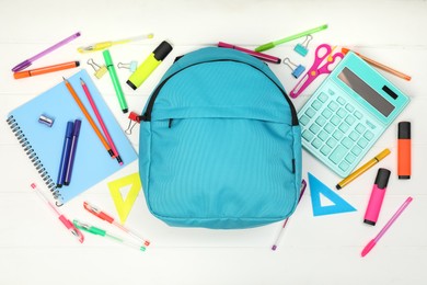 Photo of Backpack and different school supplies on white wooden background, flat lay