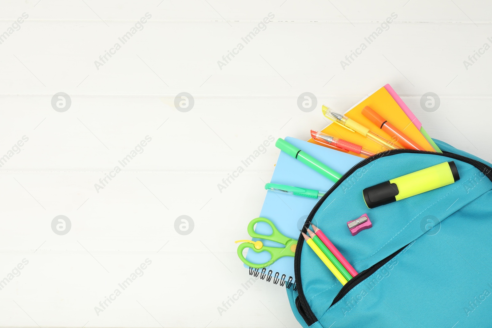 Photo of Backpack and different school supplies on white wooden background, flat lay. Space for text