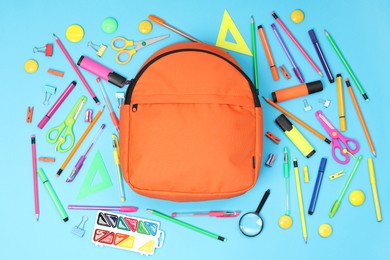 Backpack and different school supplies on light blue background, flat lay