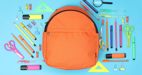 Photo of Backpack and different school supplies on light blue background, flat lay