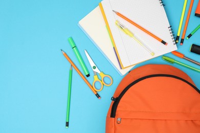 Photo of Backpack and different school supplies on light blue background, flat lay. Space for text