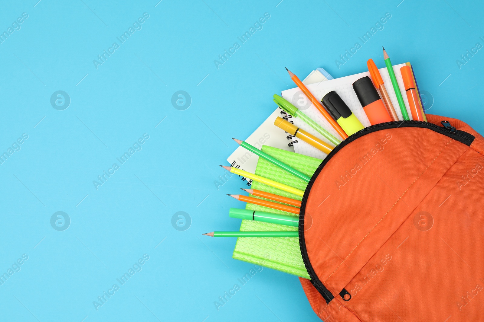 Photo of Backpack and different school supplies on light blue background, top view. Space for text