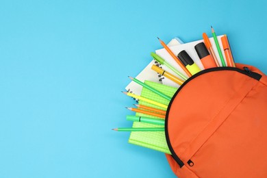 Photo of Backpack and different school supplies on light blue background, top view. Space for text