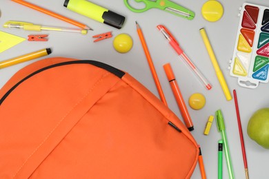 Backpack and different school supplies on light gray background, flat lay