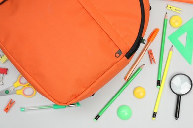 Photo of Backpack and different school supplies on light gray background, flat lay