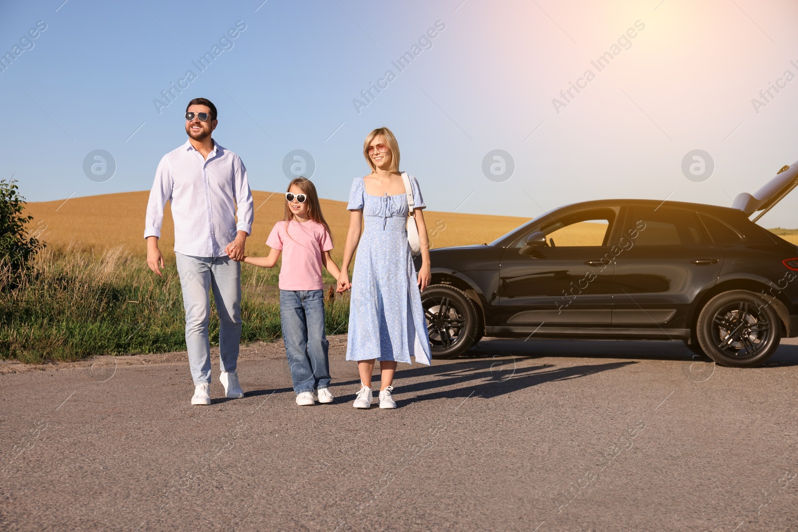 Image of Happy family enjoying road trip. Parents and daughter near car