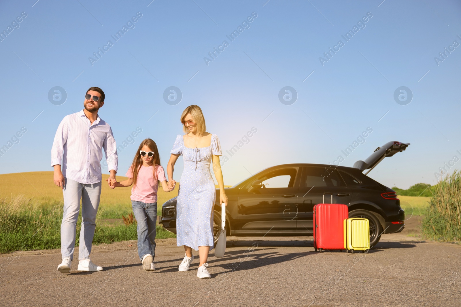 Image of Happy family enjoying road trip. Parents and daughter near car