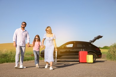 Happy family enjoying road trip. Parents and daughter near car