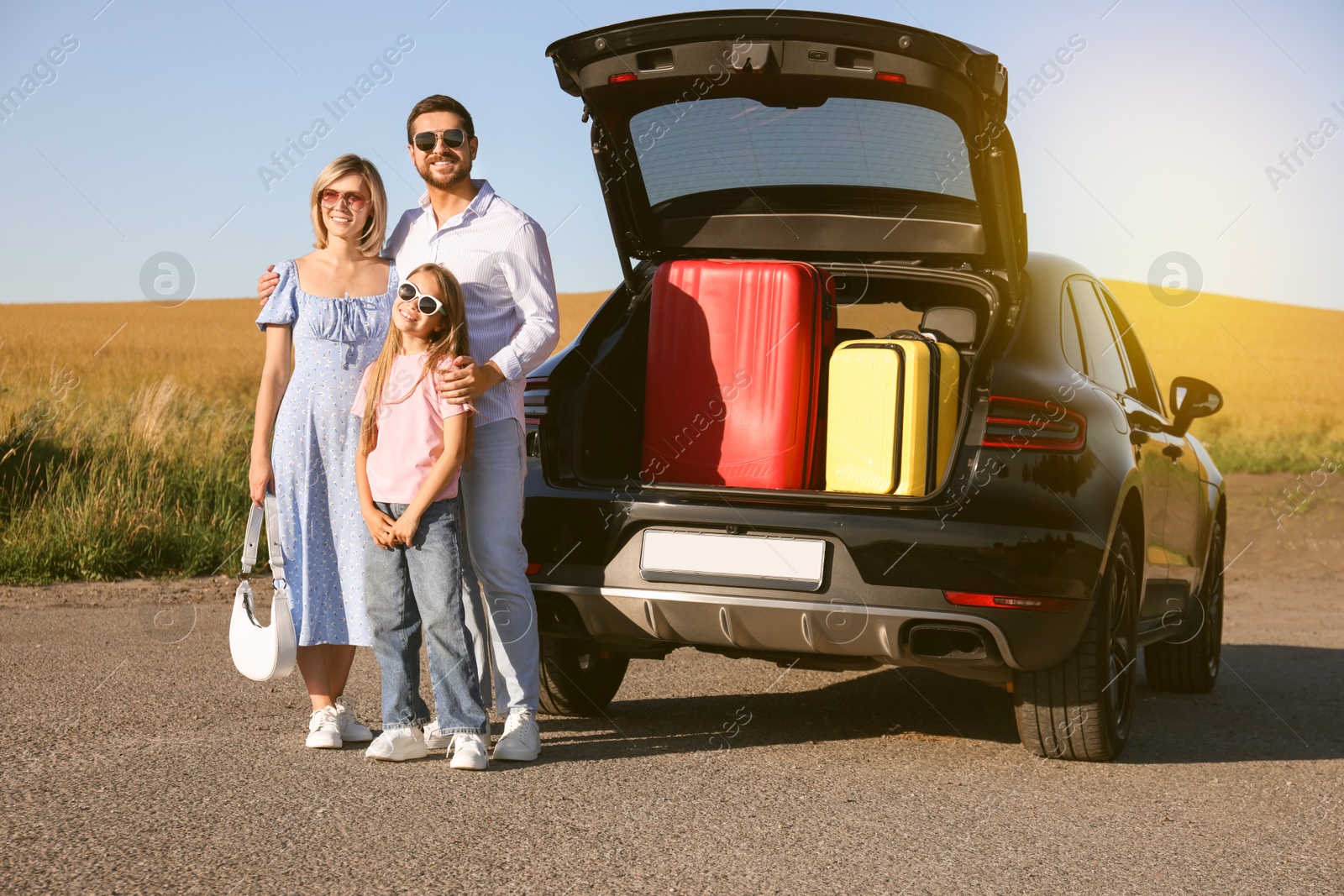 Image of Happy family enjoying road trip. Parents and daughter near car