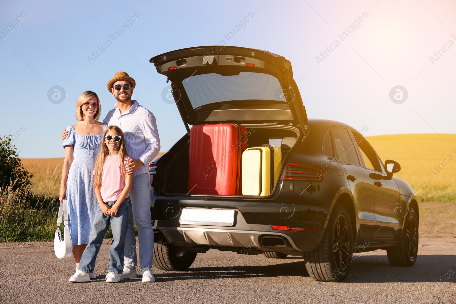 Image of Happy family enjoying road trip. Parents and daughter near car