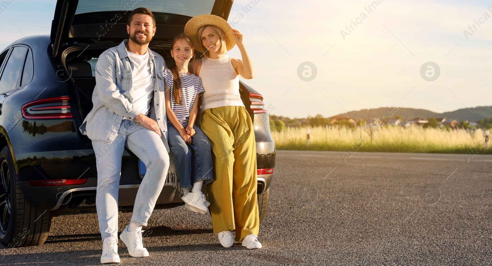 Image of Happy family enjoying road trip, banner design. Parents and daughter sitting in car trunk