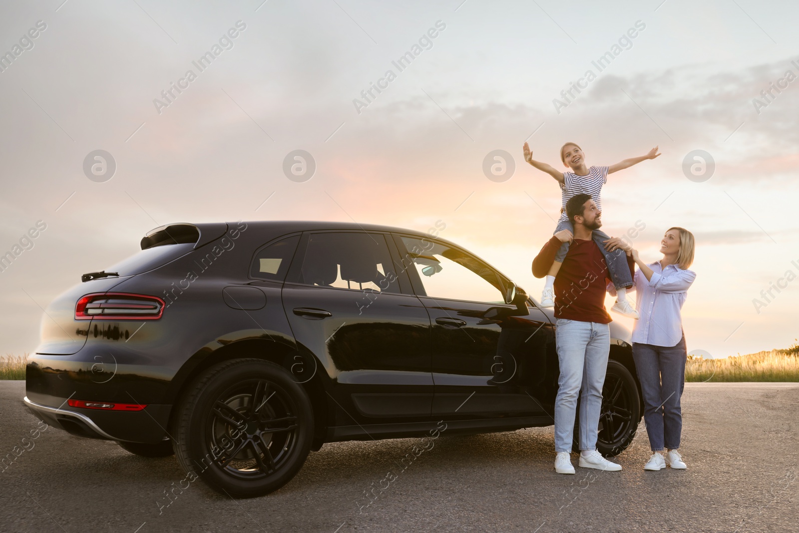 Image of Happy family enjoying road trip. Parents and daughter near car