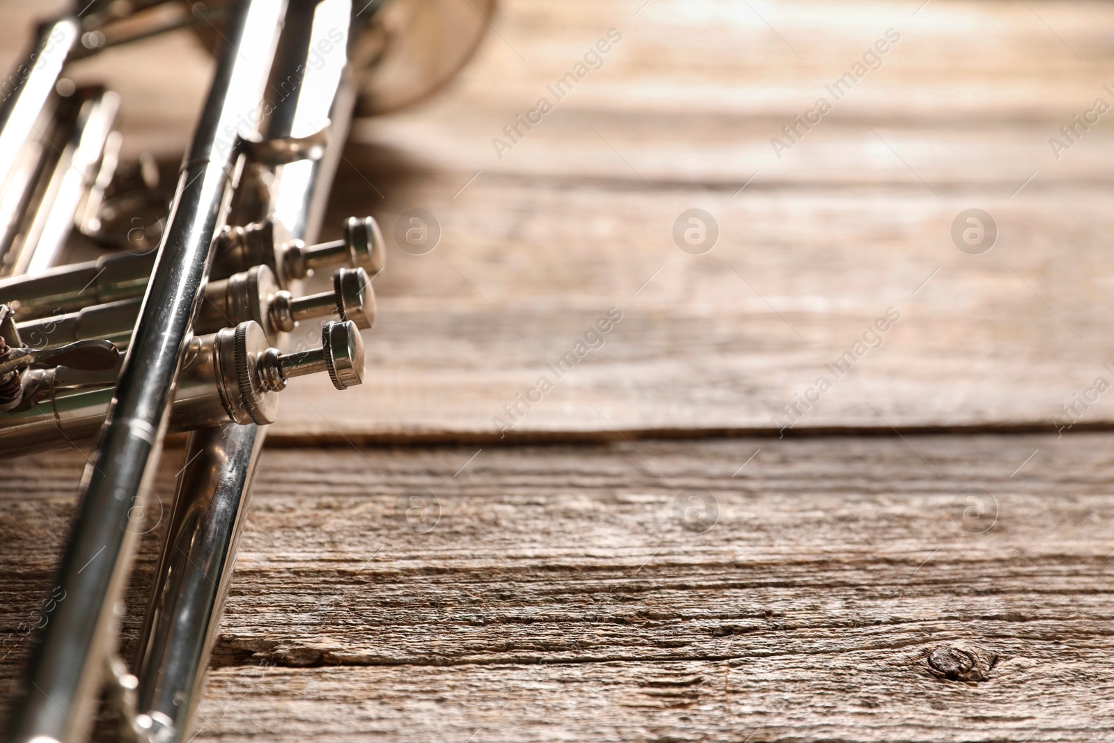 Photo of One trumpet on wooden table, closeup. Space for text