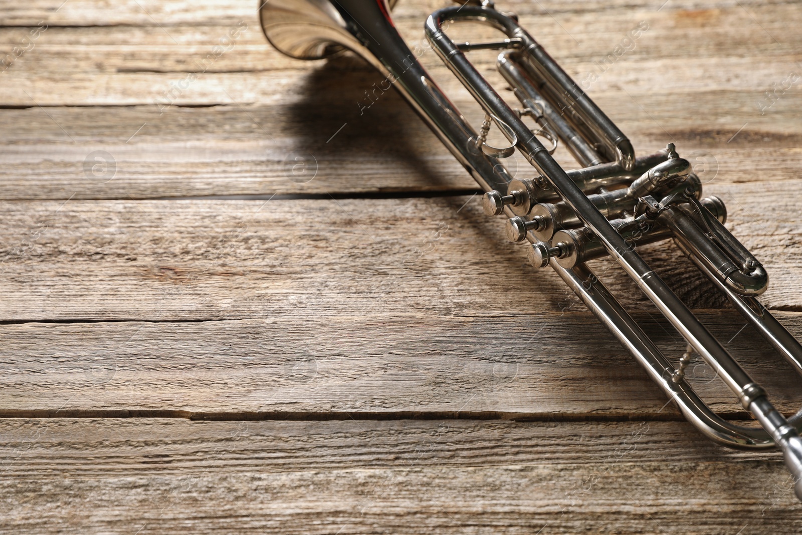 Photo of One trumpet on wooden table, closeup. Space for text