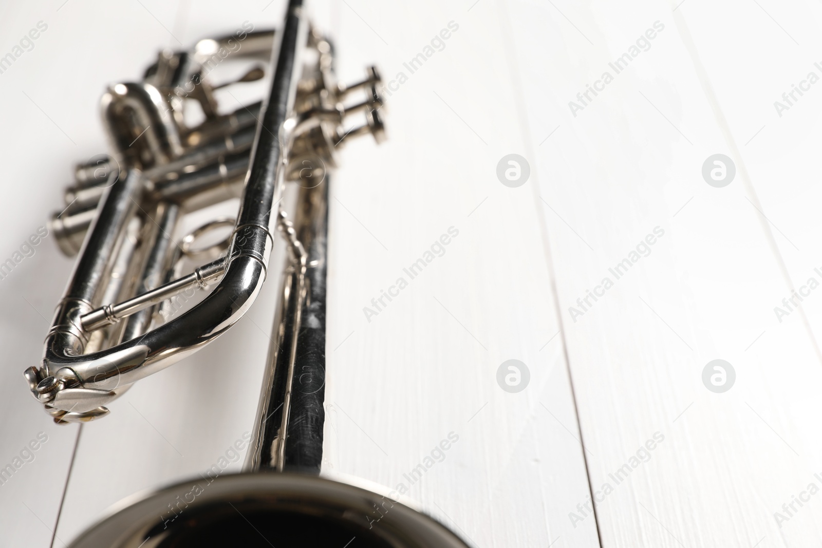 Photo of One trumpet on white wooden table, closeup. Space for text