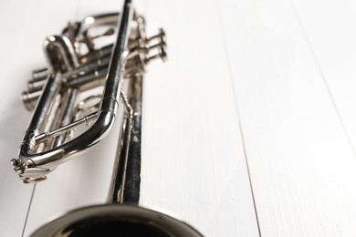 One trumpet on white wooden table, closeup. Space for text