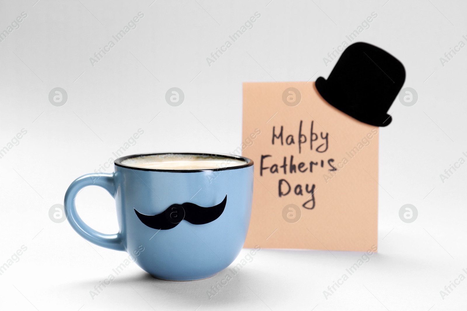 Photo of Greeting card with phrase Happy Father's Day and cup of coffee with paper moustache on light background