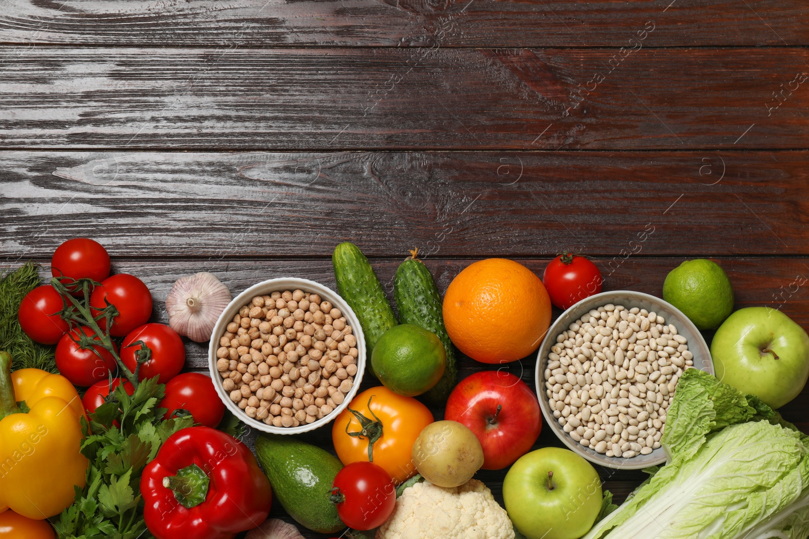 Photo of Different vegetarian products on wooden table, top view. Space for text