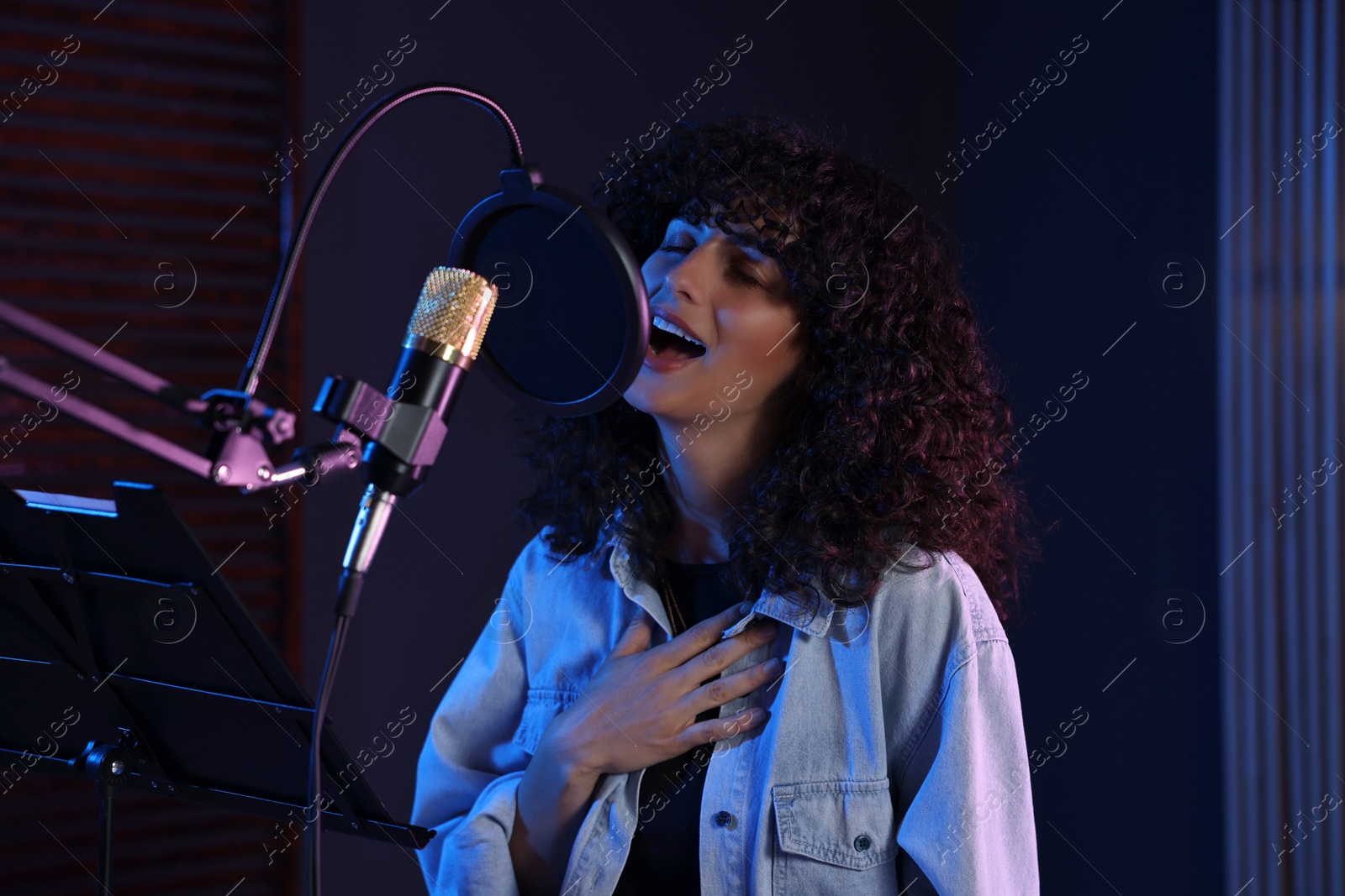 Photo of Vocalist singing into microphone in professional record studio