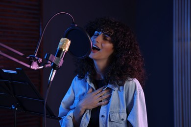 Vocalist singing into microphone in professional record studio