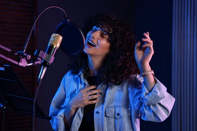 Photo of Vocalist singing into microphone in professional record studio