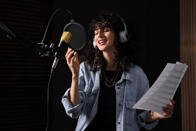 Vocalist singing into microphone in professional record studio