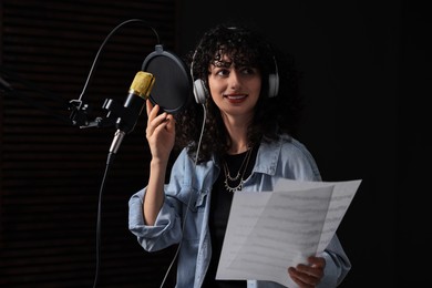 Photo of Singer wearing headphones recording song in professional studio