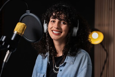 Photo of Singer with headphones recording song in professional studio