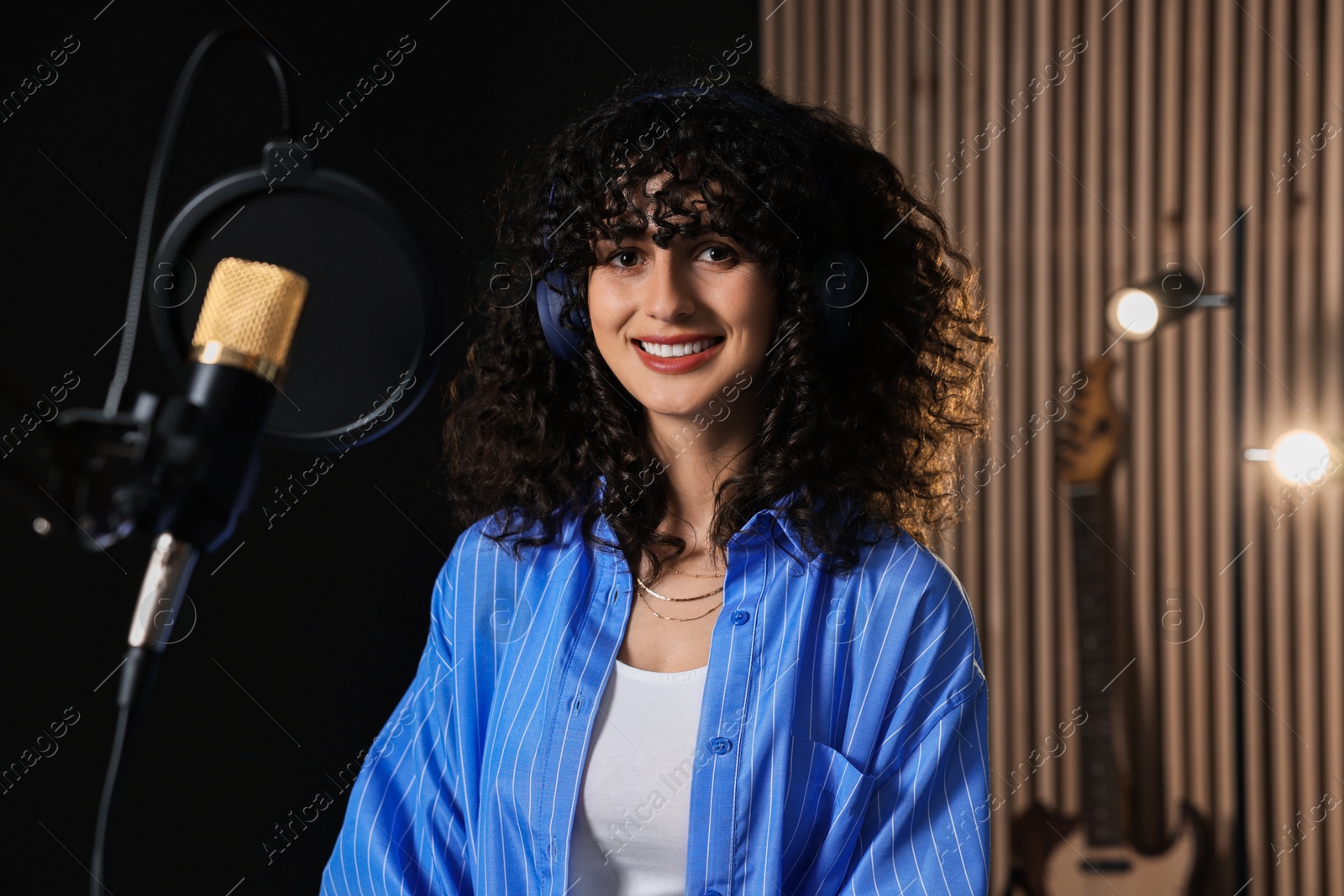 Photo of Singer with headphones recording song in professional studio