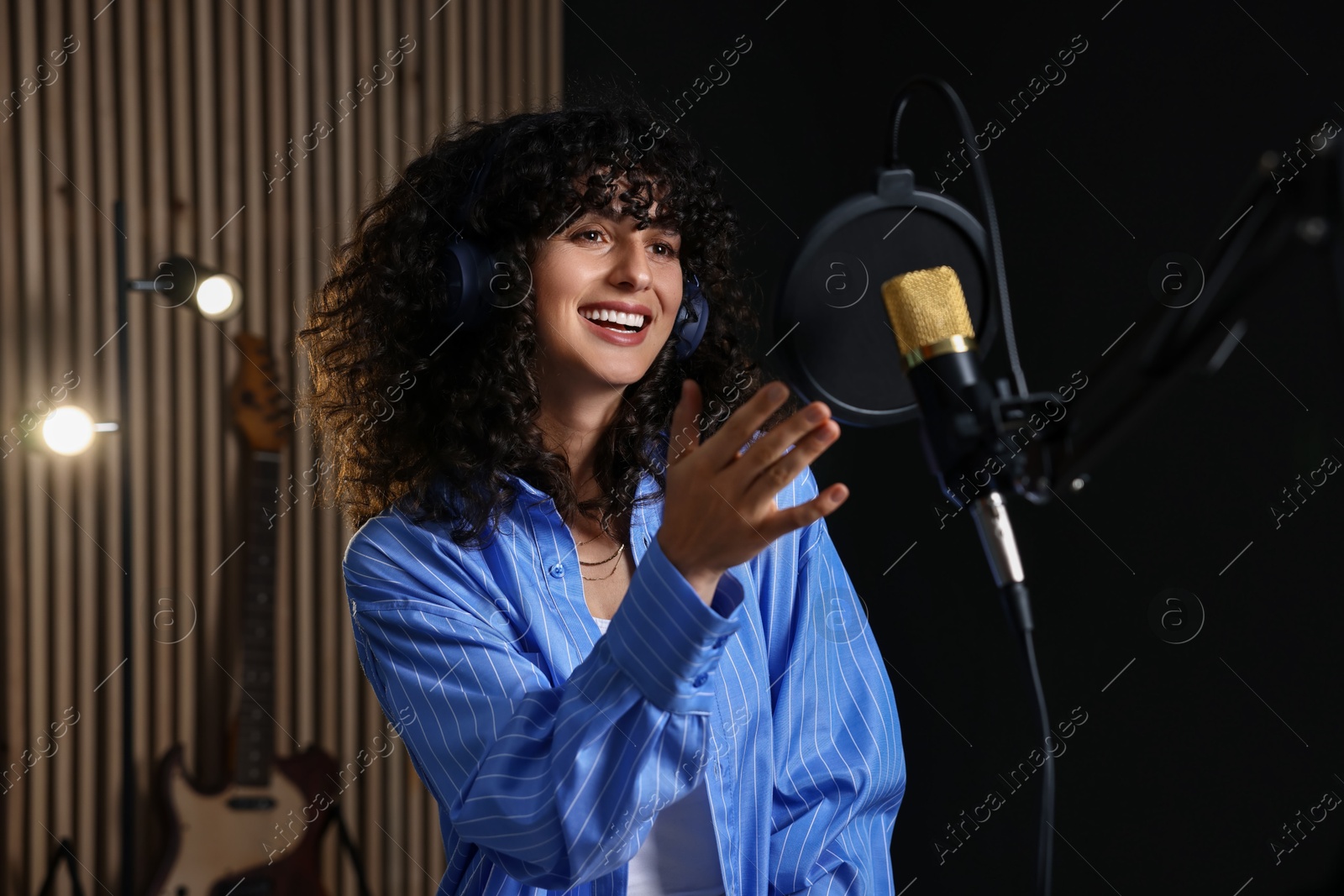 Photo of Singer with headphones recording song in professional studio