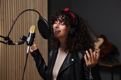 Vocalist with headphones singing into microphone in professional record studio