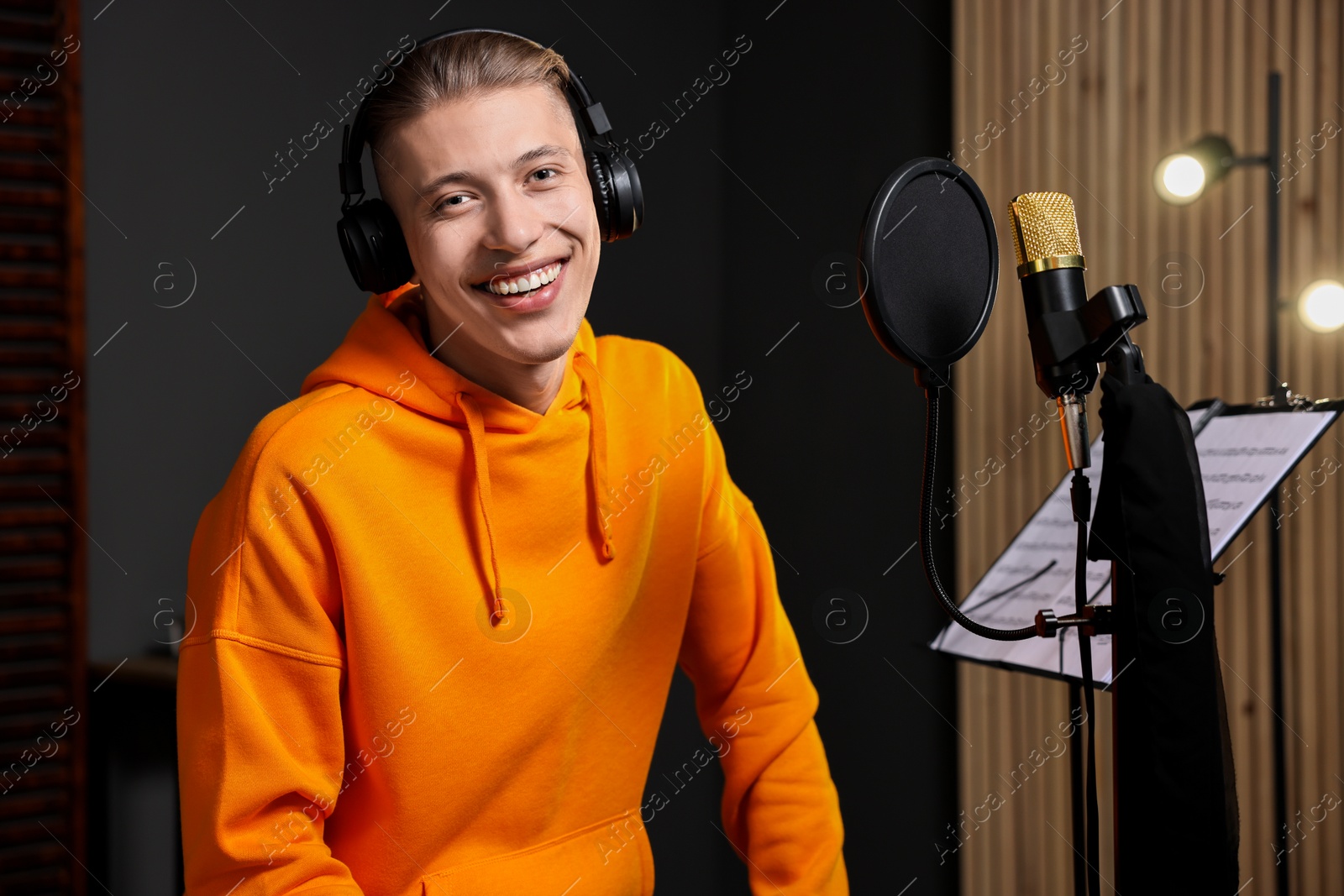 Photo of Singer with headphones recording song in professional studio