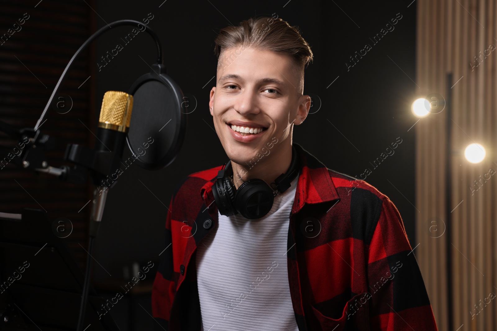 Photo of Singer with headphones recording song in professional studio