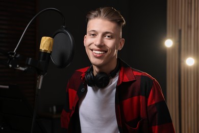 Singer with headphones recording song in professional studio