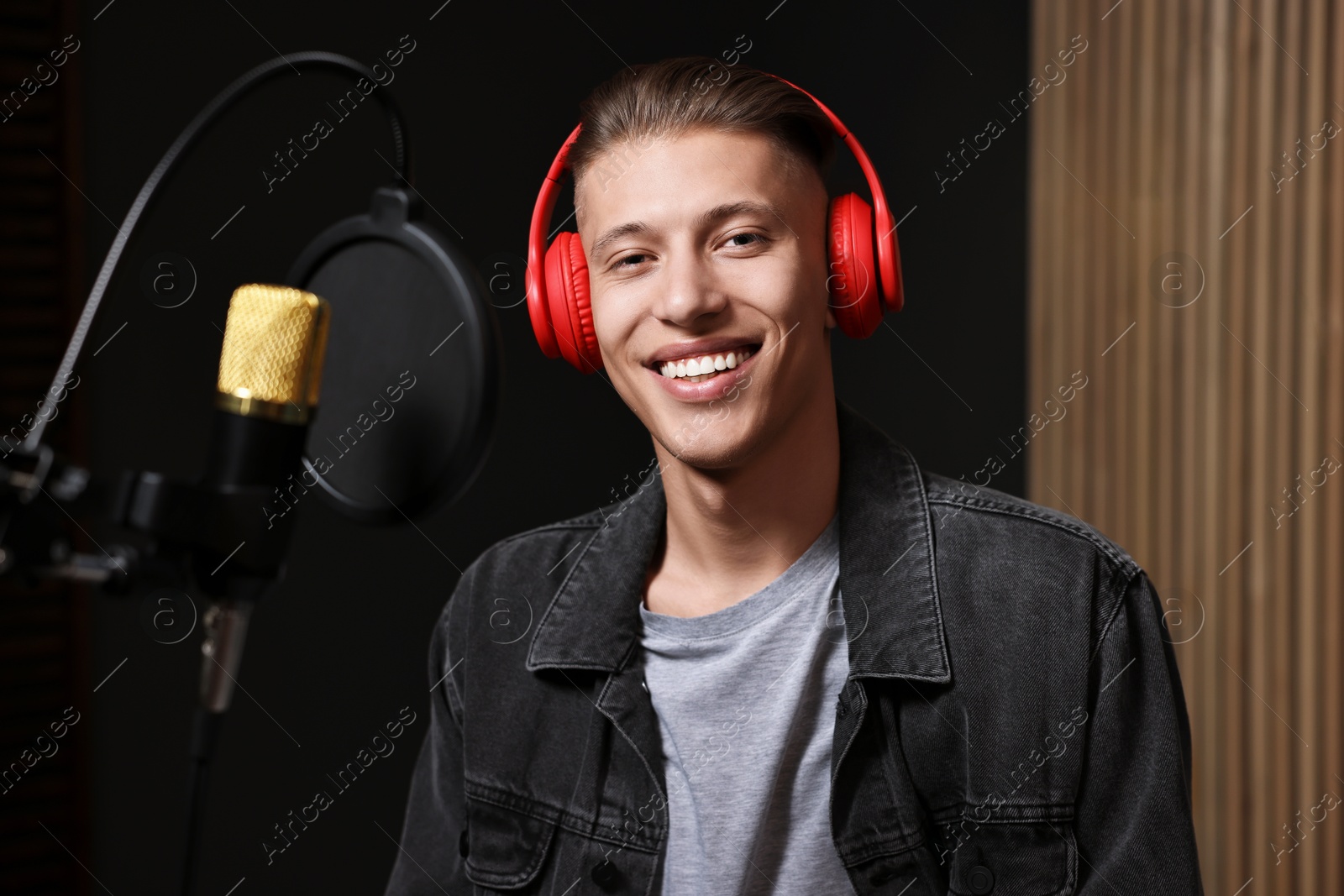 Photo of Singer with headphones recording song in professional studio