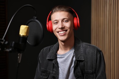 Photo of Singer with headphones recording song in professional studio