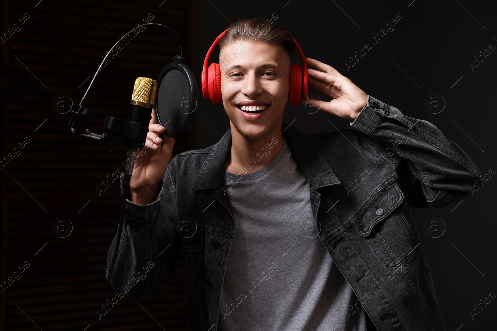 Photo of Singer with headphones recording song in professional studio