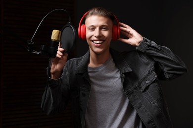 Singer with headphones recording song in professional studio