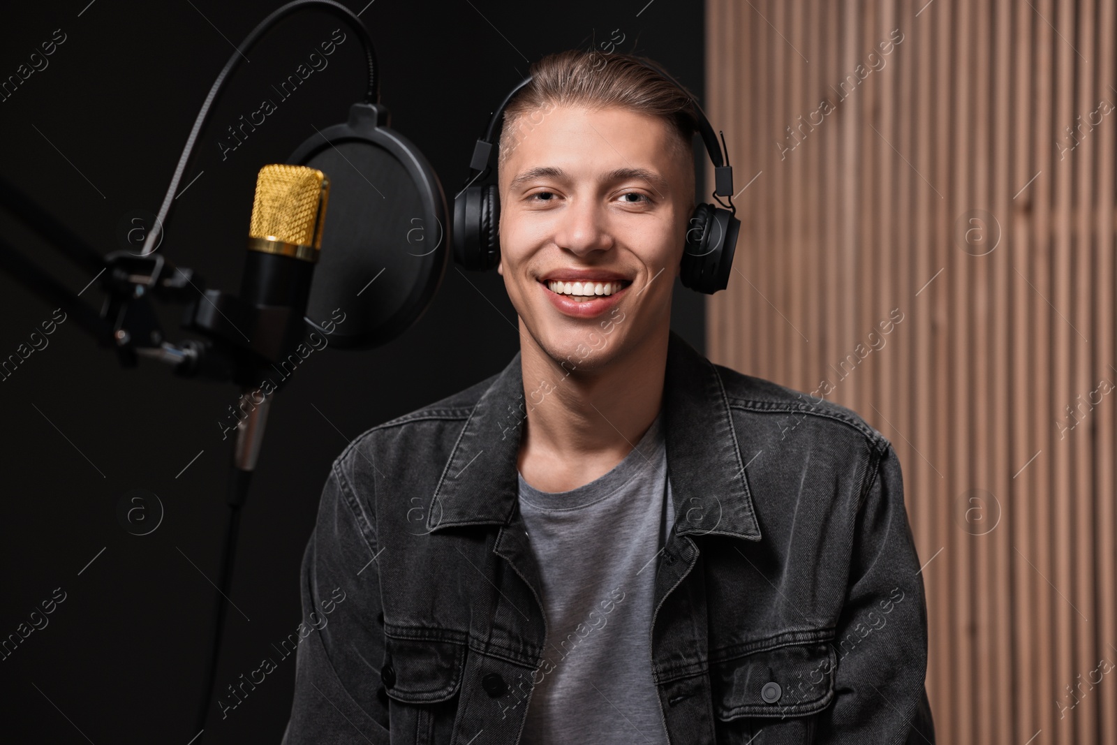 Photo of Singer with headphones recording song in professional studio