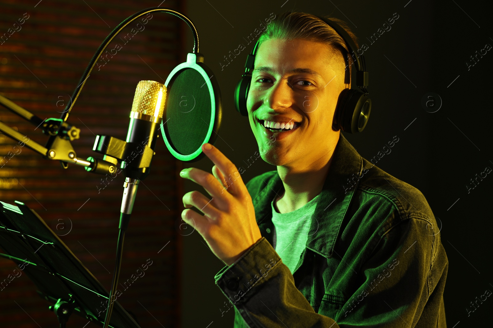 Photo of Singer with headphones recording song in professional studio