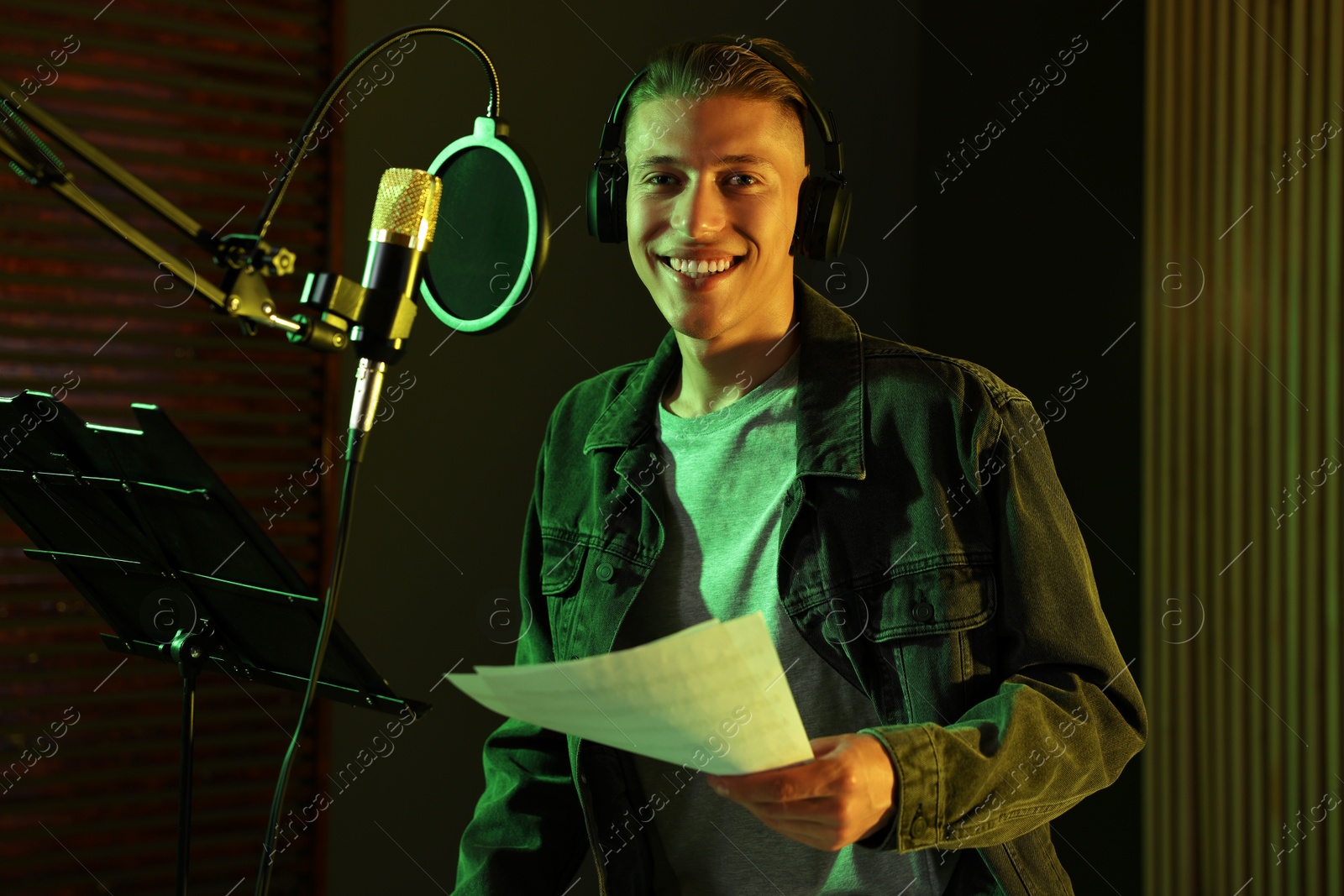 Photo of Singer with sheet recording song in professional studio