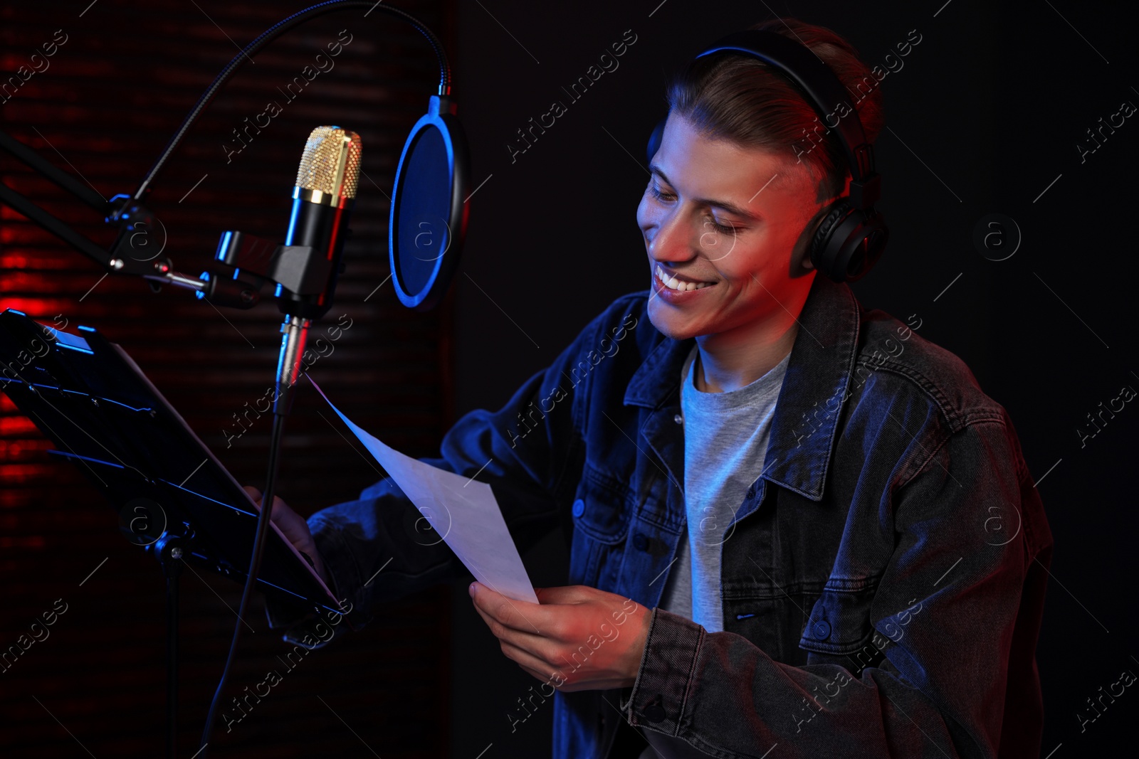 Photo of Singer with sheet recording song in professional studio